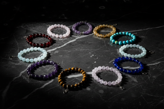 Twelve zodiac crystal bracelets arranged in a circle on dark marble — Zenora Spirit