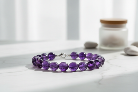 Natural amethyst crystal bracelet with deep purple beads on white marble surface